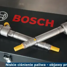 Dwa wtryskiwacze Bosch leżą na czarnej skrzynce. Mogą być przyczyną zbyt niskiego ciśnienia paliwa objawy.