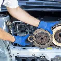Mechanik w niebieskich rękawiczkach pokazuje, jak zamontować tarczę sprzęgła i docisk.