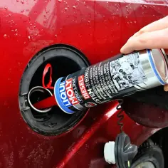 Ręka wlewa do baku czerwonego samochodu środki do czyszczenia wtryskiwaczy Liqui Moly Diesel.