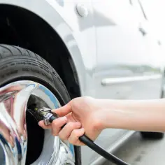 Dłoń podłącza pompkę do wentyla koła Forda Kuga. Dowiedz się, jak zresetować czujnik ciśnienia w oponach.