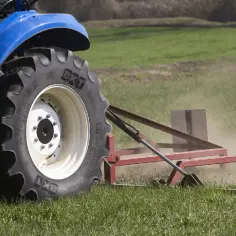 Ciągnik rolniczy z wielką oponą BKT AgriMax pracuje na polu. Zastanawiasz się, ile waży opona rolnicza?