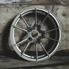 Felga aluminiowa z wieloma ramionami na tle industrialnym.