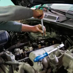 Mechanik precyzyjnie wykonuje czyszczenie gniazd wtryskiwaczy, używając klucza nasadowego do precyzyjnej pracy przy silniku.