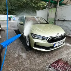 Mycie auta na samoobsługowej myjni. Woda pod ciśnieniem spływa po masce, pomagając usunąć żywicę z lakieru samochodu.