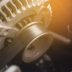 Metalowy alternator samochodowy z paskiem napędowym. To serce układu ładowania, co to jest alternator?