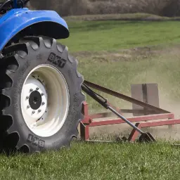 Ciągnik rolniczy z wielką oponą BKT AgriMax pracuje na polu. Zastanawiasz się, ile waży opona rolnicza?