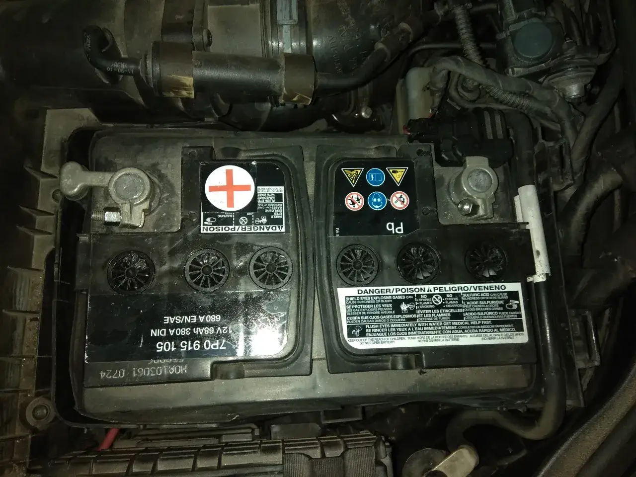 Akumulator Passat B6 2.0 TDI, widoczny w komorze silnika, z oznaczeniami i ostrzeżeniami.